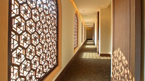 A corridor with patterned floor tiles, wooden walls, and decorative screens.