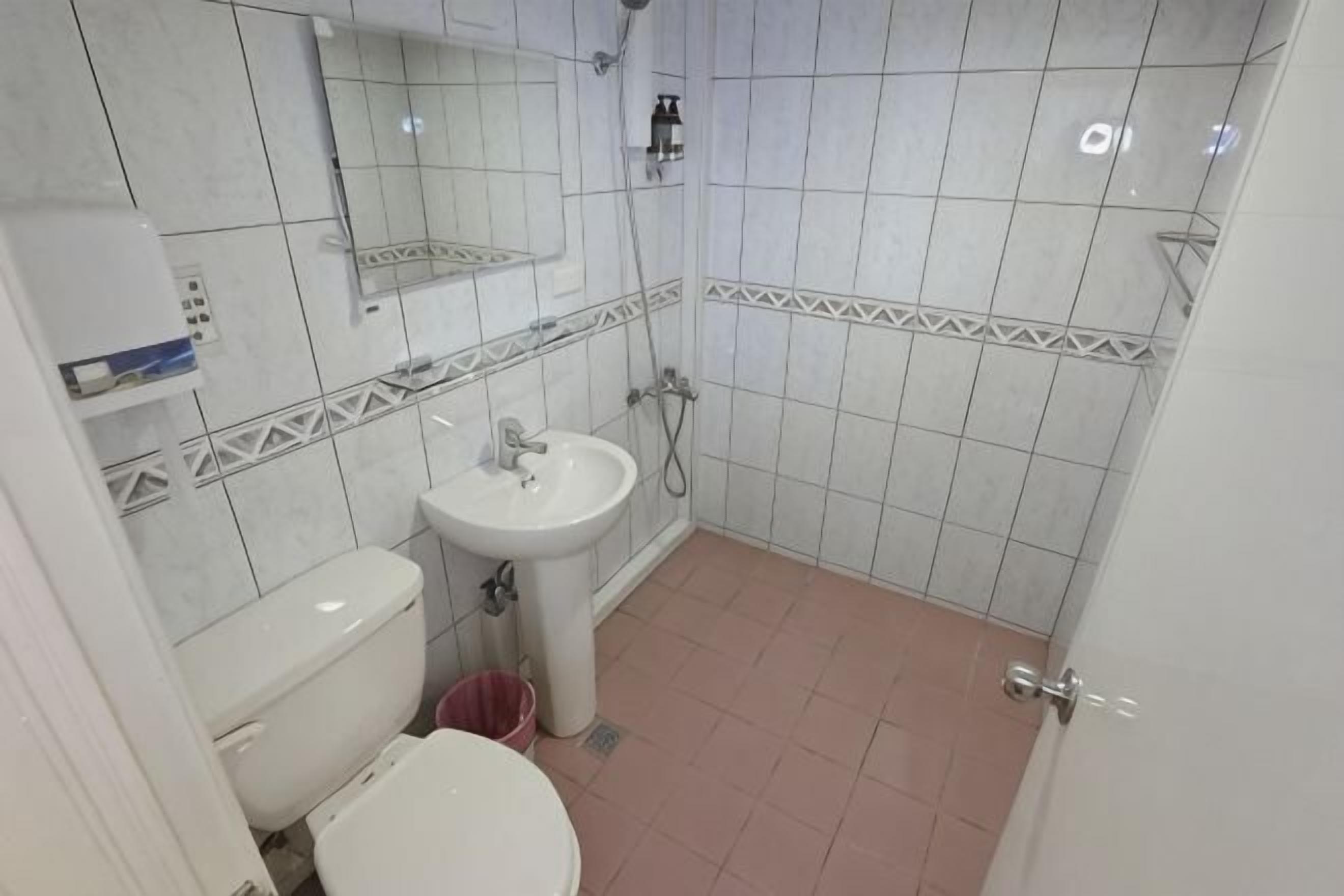 A small bathroom with a toilet, sink, and shower.