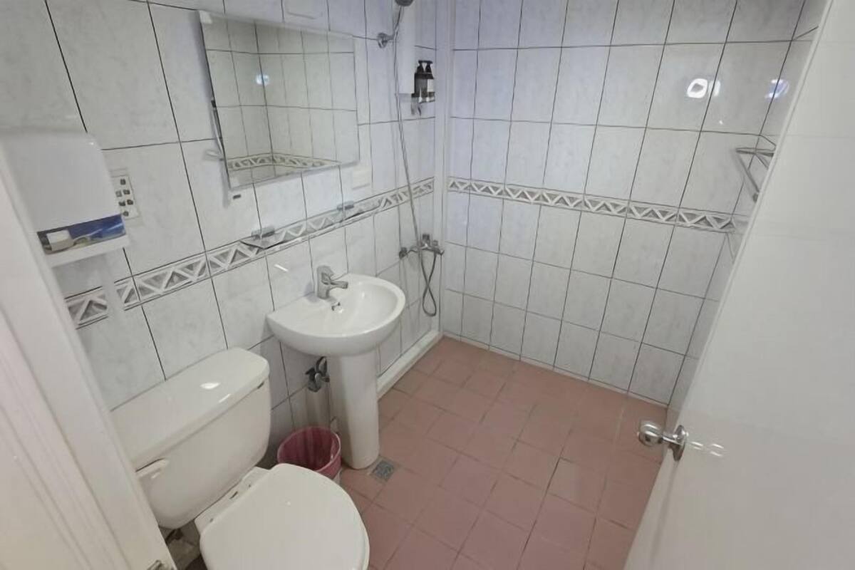 A small bathroom with a toilet, sink, and shower.