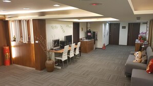 Eine Hotelhalle mit Rezeption, Sitzgelegenheiten und einer Couch.