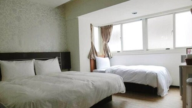 Ein Hotelzimmer mit zwei Betten, einem großen Fenster und einem Holzboden.