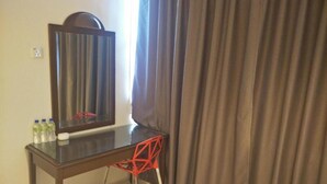 A room with a wooden desk, a mirror, a red chair, and a white bucket. - T Hotel Anggerik (Alor Setar)