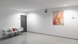 A modern, minimalist lobby with a reception desk, a door, and a large abstract painting on the wall. - T Hotel Anggerik (Alor Setar)