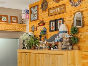 Una reception in legno con un cartello che riporta la scritta 'BISTRO', circondata da decorazioni a tema nautico e opere d'arte incorniciate.