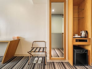 A hotel room with a bed, a small table with a kettle, a trash bin, and a shoe rack. - Guide Education Culture Hotel Kaohsiung Museum of Fine Arts (Kaohsiung)