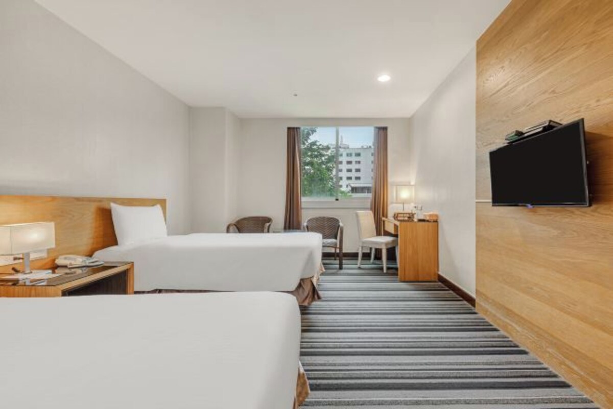 Una habitación de hotel con dos camas, televisión, escritorio y una silla.