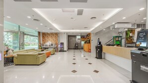 Um saguão de hotel com balcão de recepção, área de estar e posto de check-in.