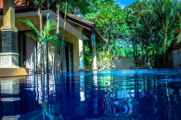 Vista despejada de una piscina que refleja los árboles circundantes y un edificio con tejado de azulejos.