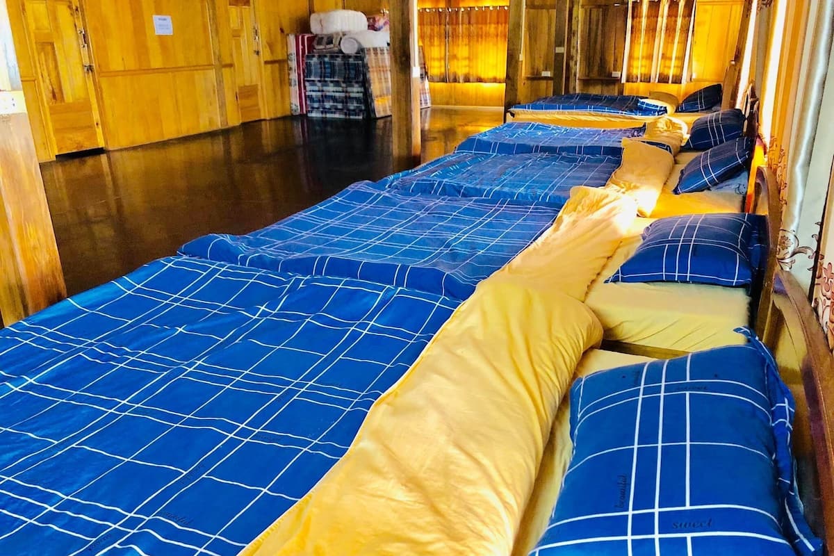 A row of beds with blue and yellow bedding in a wooden room.