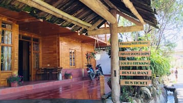 A wooden building with a covered porch, a sign listing amenities like a private room, dining, and a restaurant.