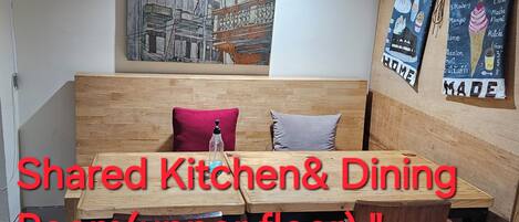 Cocina y comedor compartidos en el piso superior, con muebles de madera y un cuadro de paisaje urbano en la pared.