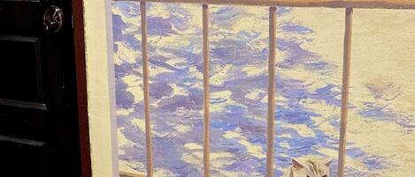 Una cama con toallas enrolladas y dos gatos sentados junto a una ventana con una vista pintada.