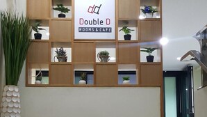 A wall with a sign for 'Double D Rooms & Cafe' and a wooden shelf with potted plants. - Double D Rooms & Cafe (Bangkok)
