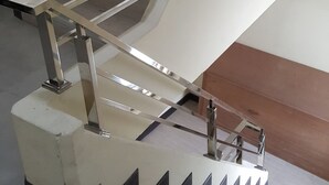 A set of modern, metallic staircases with glass railings and a wooden finish on the steps. - Double D Rooms & Cafe (Bangkok)