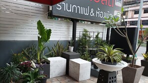 A hotel entrance with a signboard, potted plants, and a tiled floor. - Double D Rooms & Cafe (Bangkok)