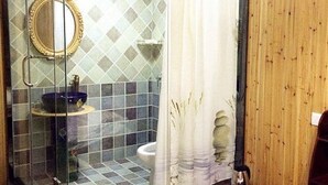 Une salle de bain avec une douche à parois de verre, un lavabo avec un receveur bleu, des toilettes et un miroir.