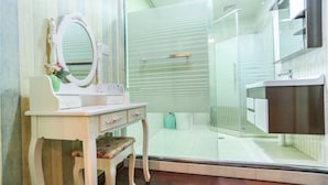 Une salle de bain équipée d’un meuble-lavabo, d’un miroir, d’une douche et de toilettes.