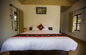 Una cama grande con una colcha blanca y roja, dos almohadas y un cuadro en la pared.