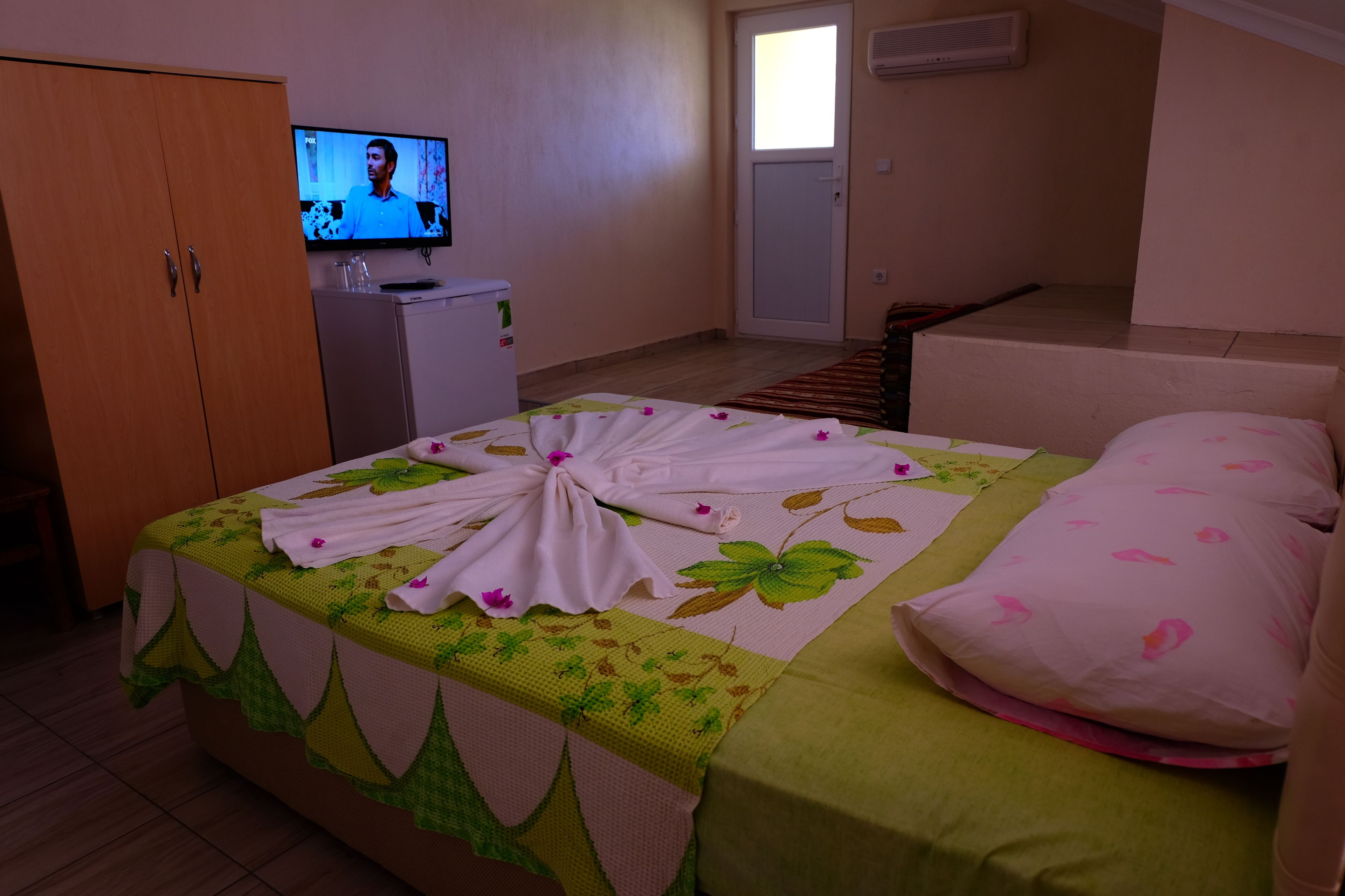 A hotel room with a bed, a television, a small desk, and a wardrobe.