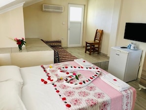 A hotel room with a bed, a small desk, a chair, a television, and a refrigerator. - Karaca Apart Hotel (Ortaca)