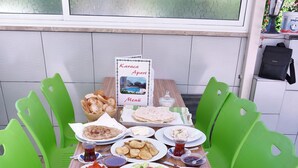 A table set for a meal with various dishes, a menu, and green plastic chairs. - Karaca Apart Hotel (Ortaca)