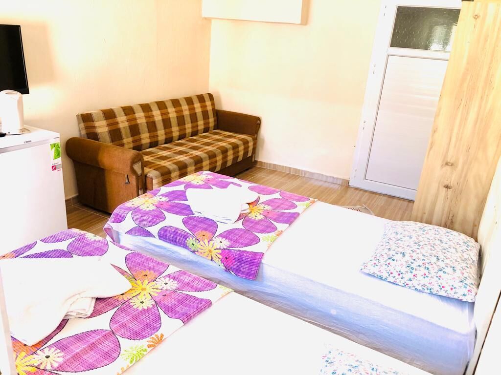 A room with a bed, a sofa, a small table with a lamp, and a wardrobe.