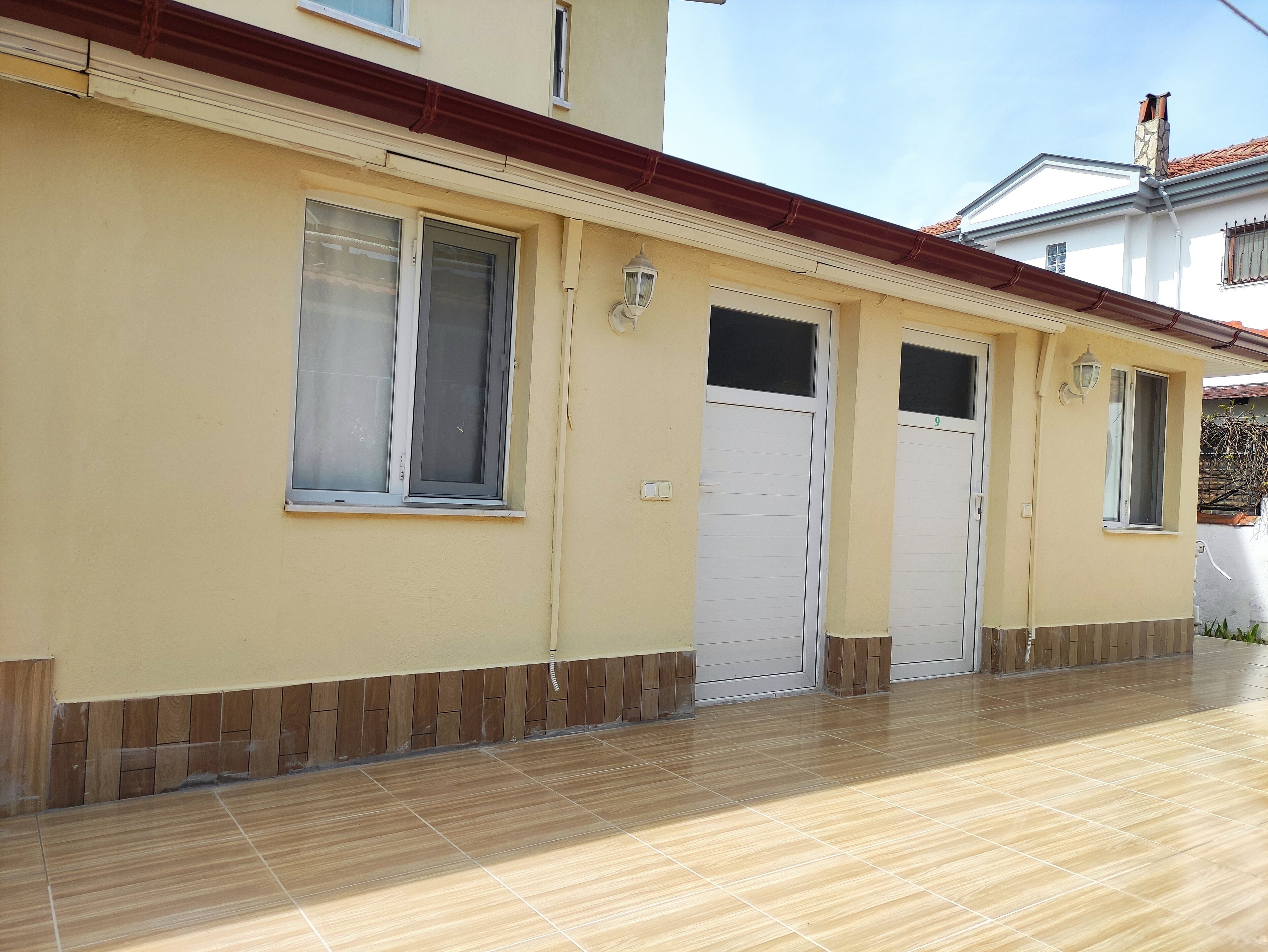 A two-story building with a yellow facade, two white doors, and a tiled floor.