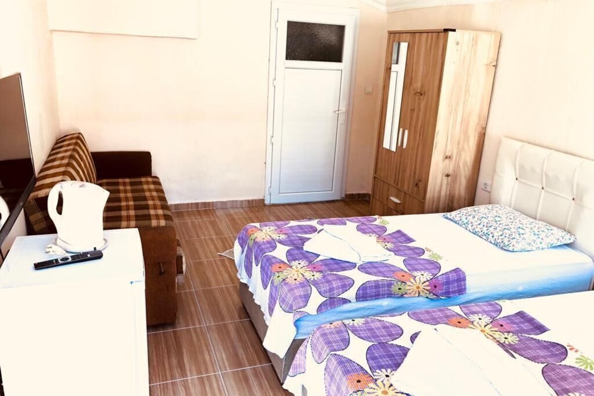 A room with a bed, a desk, a chair, a wardrobe, and a door.