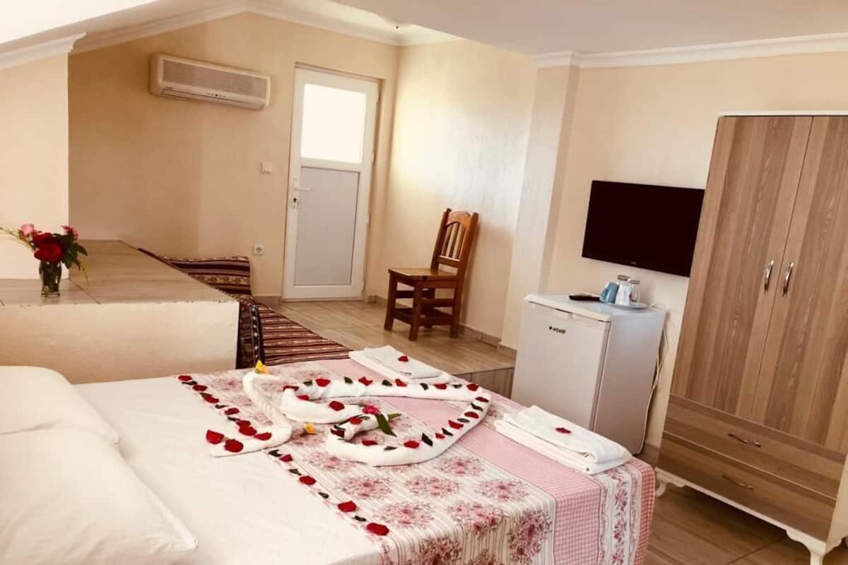 A bedroom with a bed, a chair, a TV, a wardrobe, and a small desk.