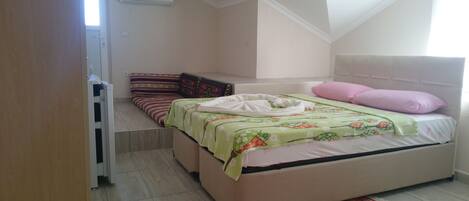 A bedroom with a bed, pillows, a blanket, a rug, and a window.