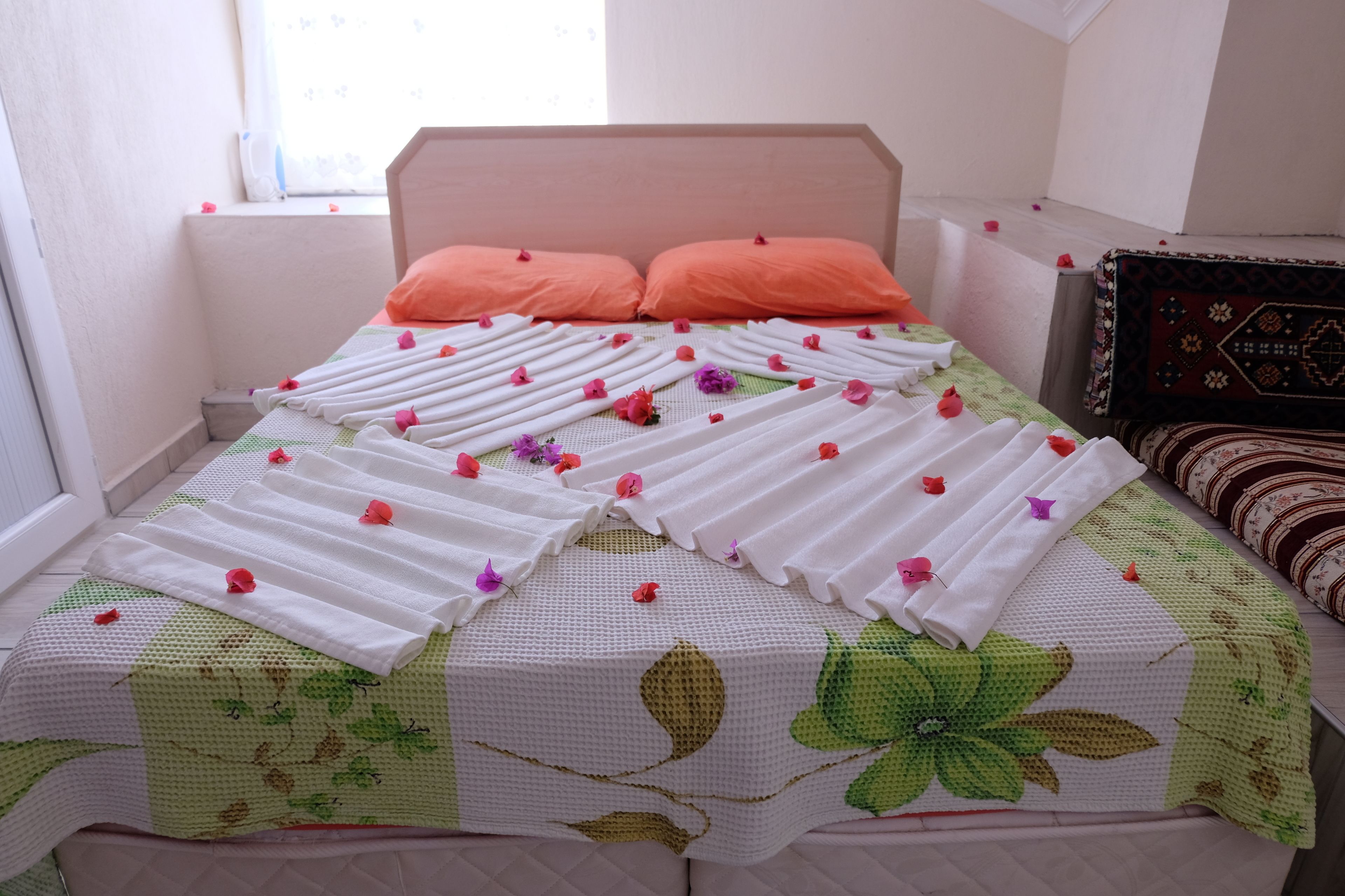 Ein ordentlich bezogenes Bett mit Blumenmuster, zwei Kissen und einem Kopfteil.
