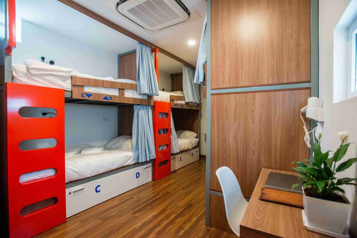 Quarto compacto com beliches, escrivaninha e cadeira.
