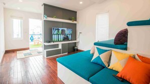 Una sala de estar moderna con un sofá, un televisor y un ventanal.