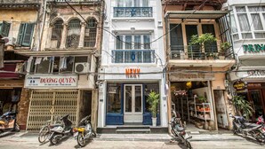 Un hotel con entrada azul, un letrero que dice Duong Quyen y motocicletas estacionadas afuera.