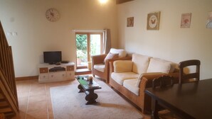 A living room with a television, sofa, and dining table. - Gîtes de Campagne (Fursac)