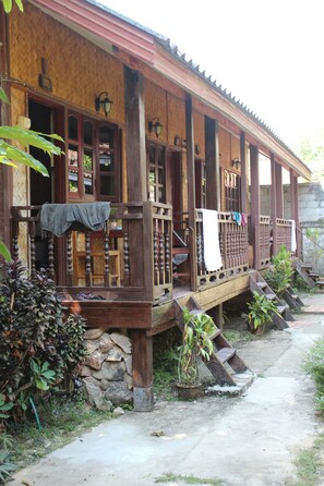 Un bâtiment traditionnel en bois, doté d’un porche, d ’un escalier en pierre et d’un petit jardin.