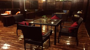 Un espace de détente intérieur accueillant, avec des fauteuils en osier et une table en verre, un plancher en bois et une atmosphère chaleureuse.