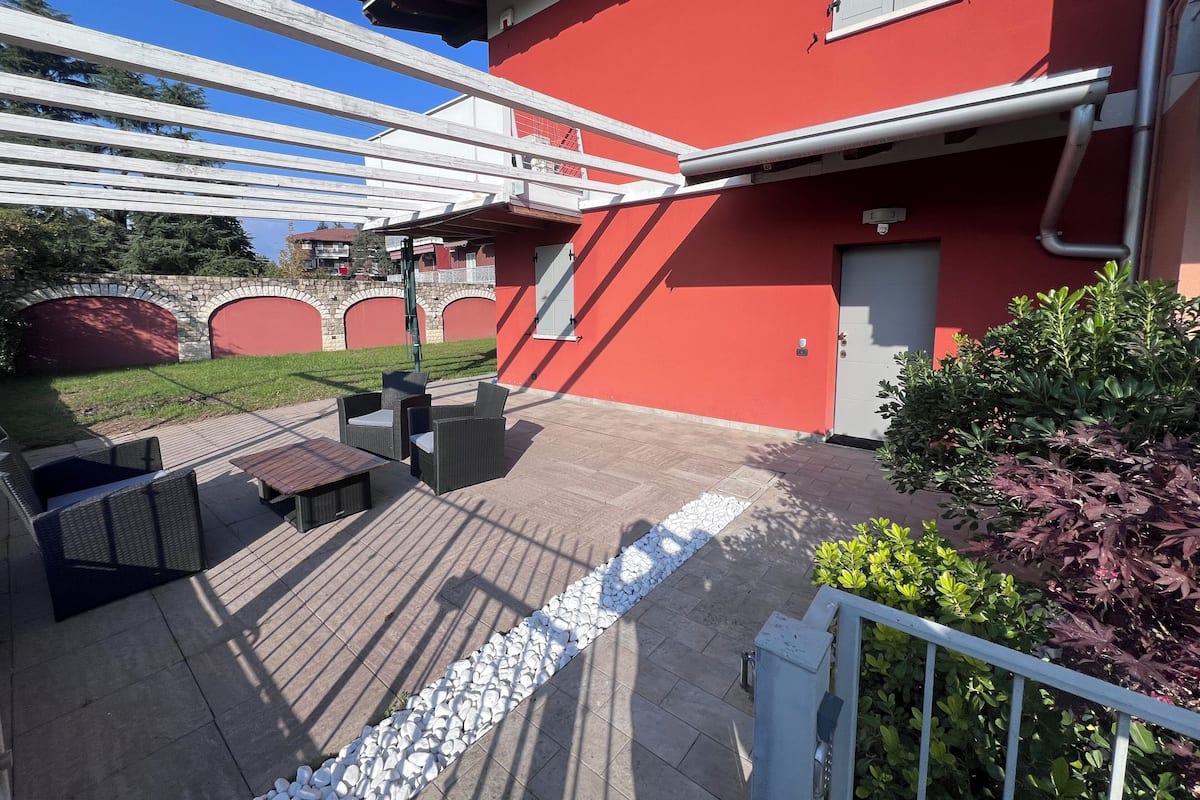 A red building with a covered patio area featuring outdoor furniture and a stone pathway.