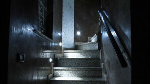Una escalera de granito con barandilla que lleva a un piso superior.