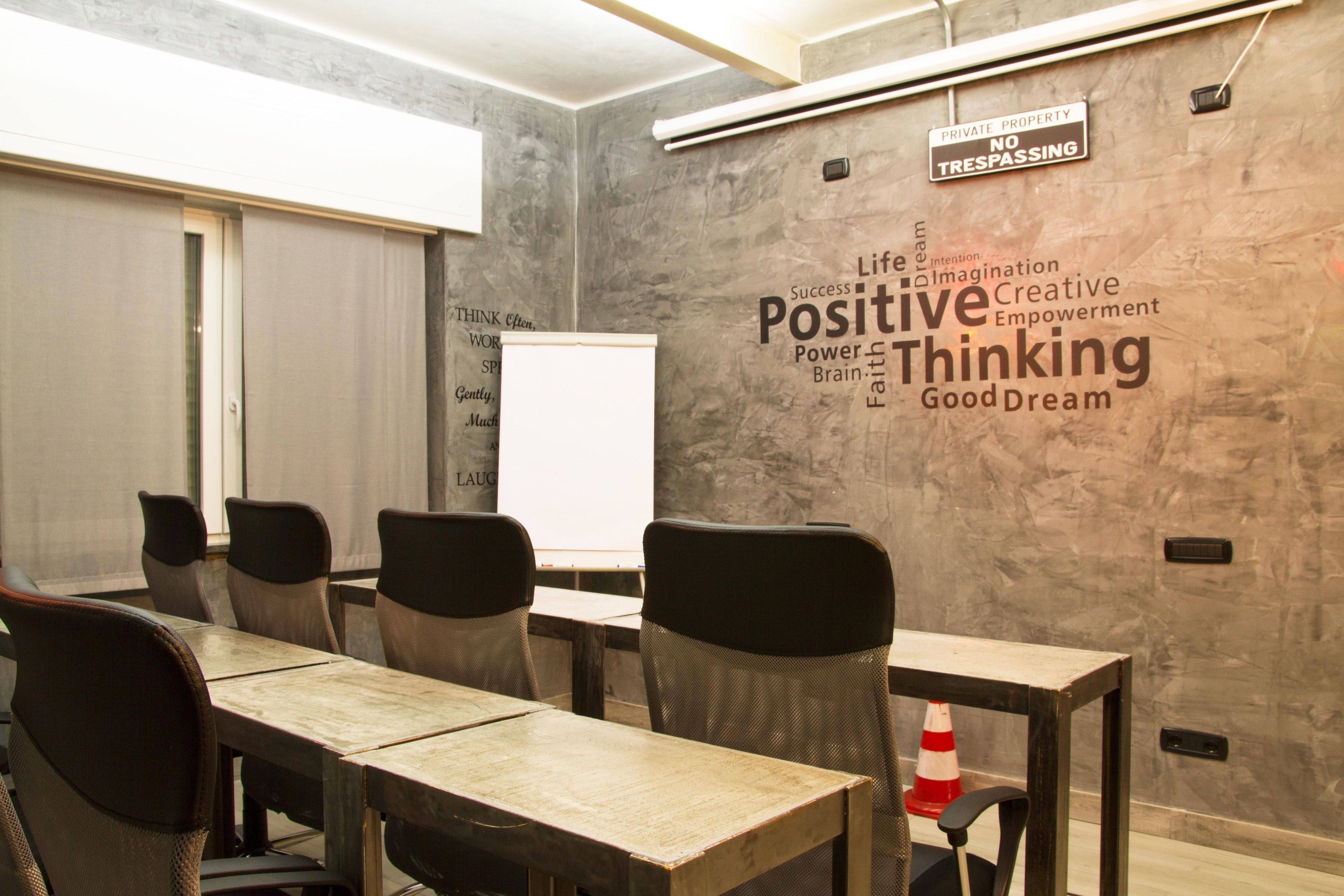 Een vergaderruimte met een marmeren wand met motiverende woorden, een whiteboard en een tafel met stoelen.