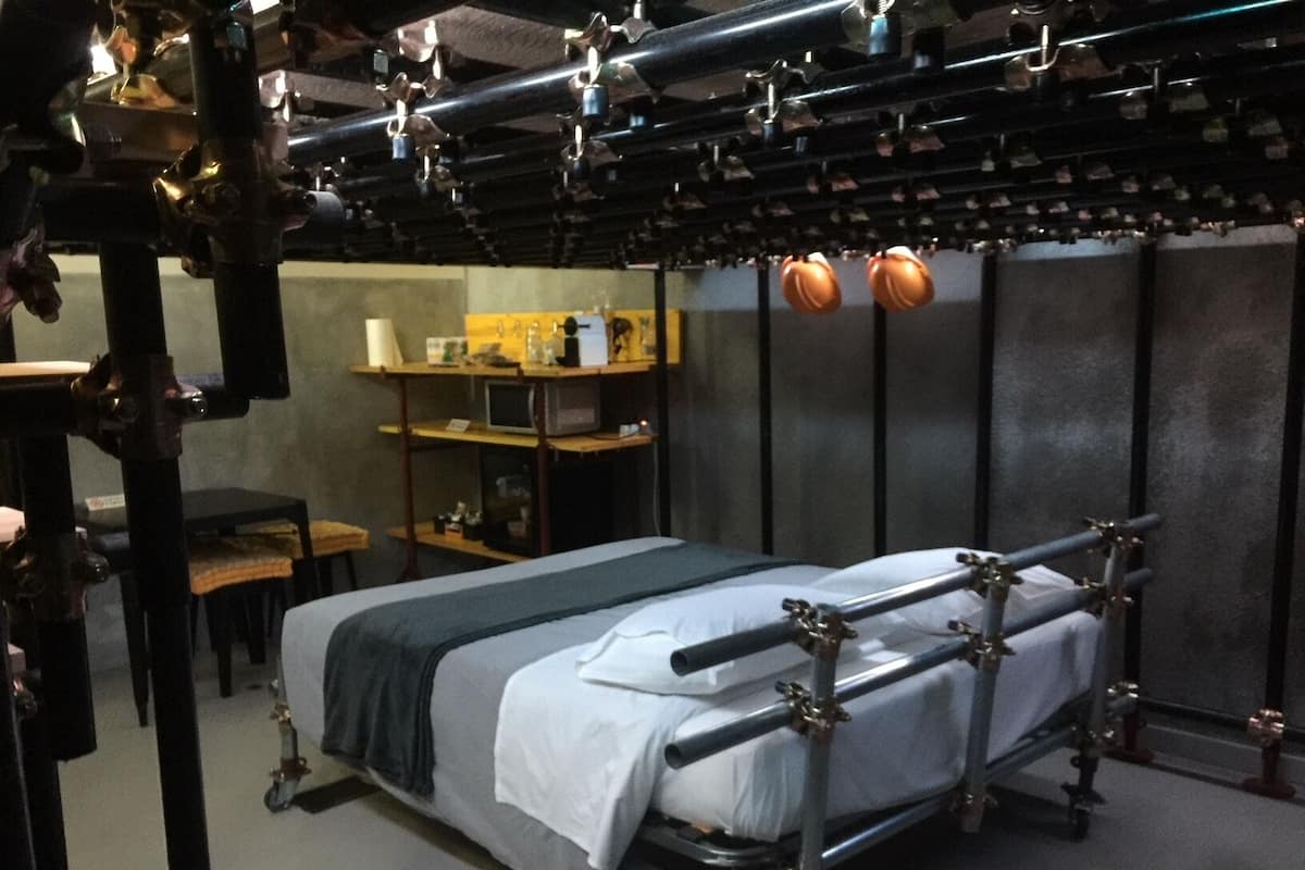 A modern hotel room with a metal bed frame, a desk, and a chair.