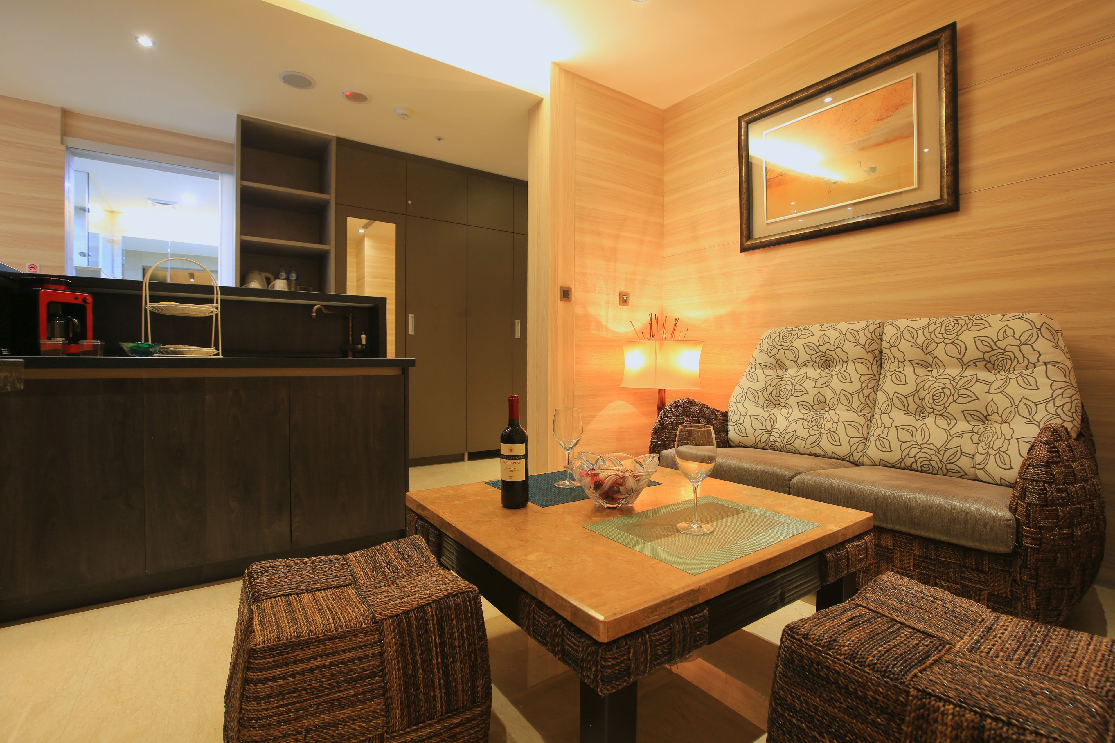 A modern living room with a sofa, a coffee machine, and a dining table with a wine bottle and glasses.