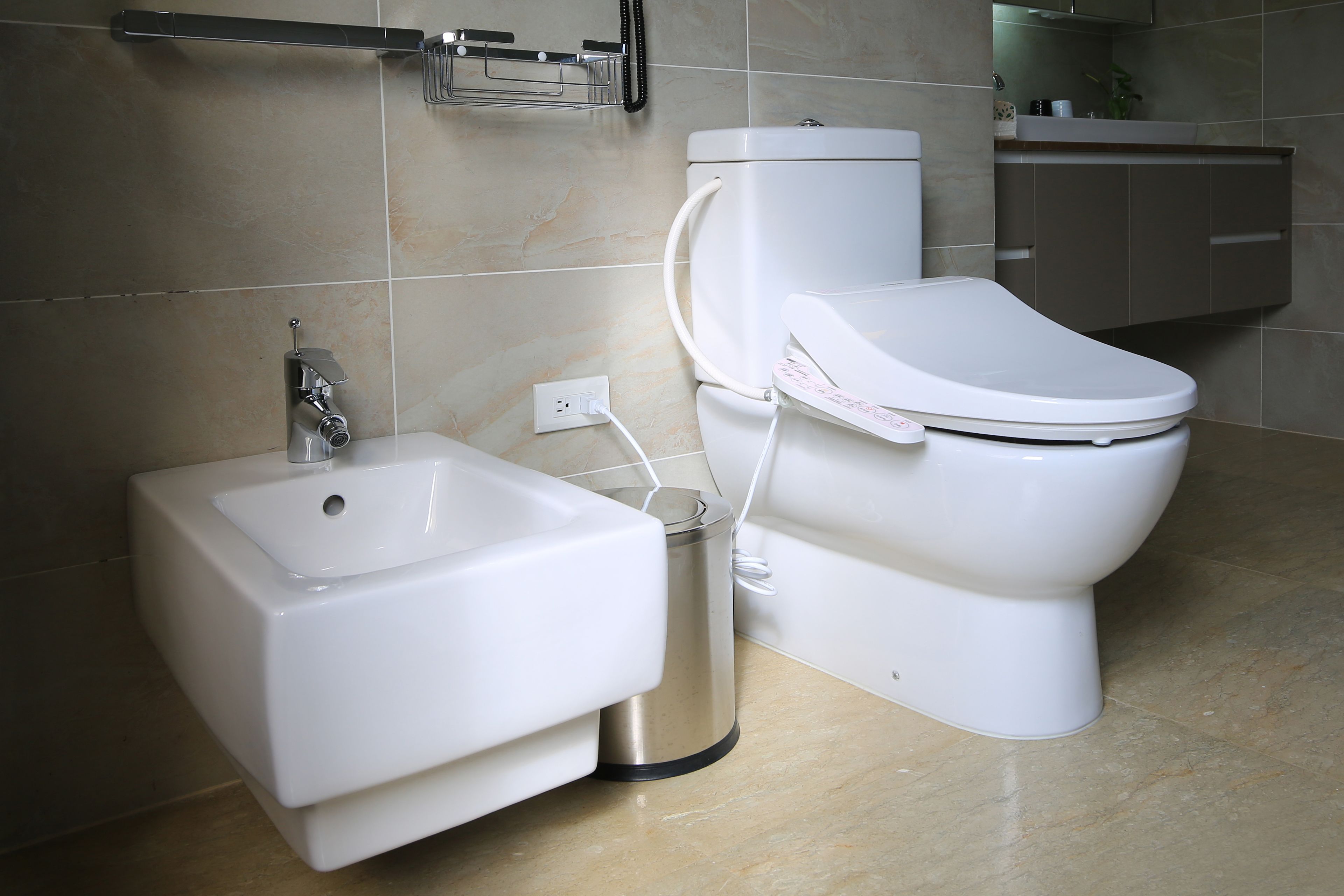 Un baño moderno con un lavamanos, inodoro y un cubo de basura blancos.
