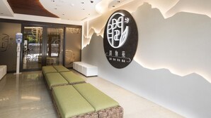 A modern interior with a reception desk, seating area, and a wall-mounted sign. - Dar Lon Hotel (Hsinchu)