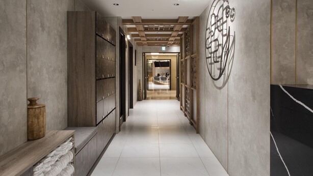 A corridor with a wooden bench, a wall-mounted decorative piece, and a tiled floor. - Dar Lon Hotel (Hsinchu)