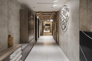 A corridor with a wooden bench, a wall-mounted decorative piece, and a tiled floor. - Dar Lon Hotel (Hsinchu)