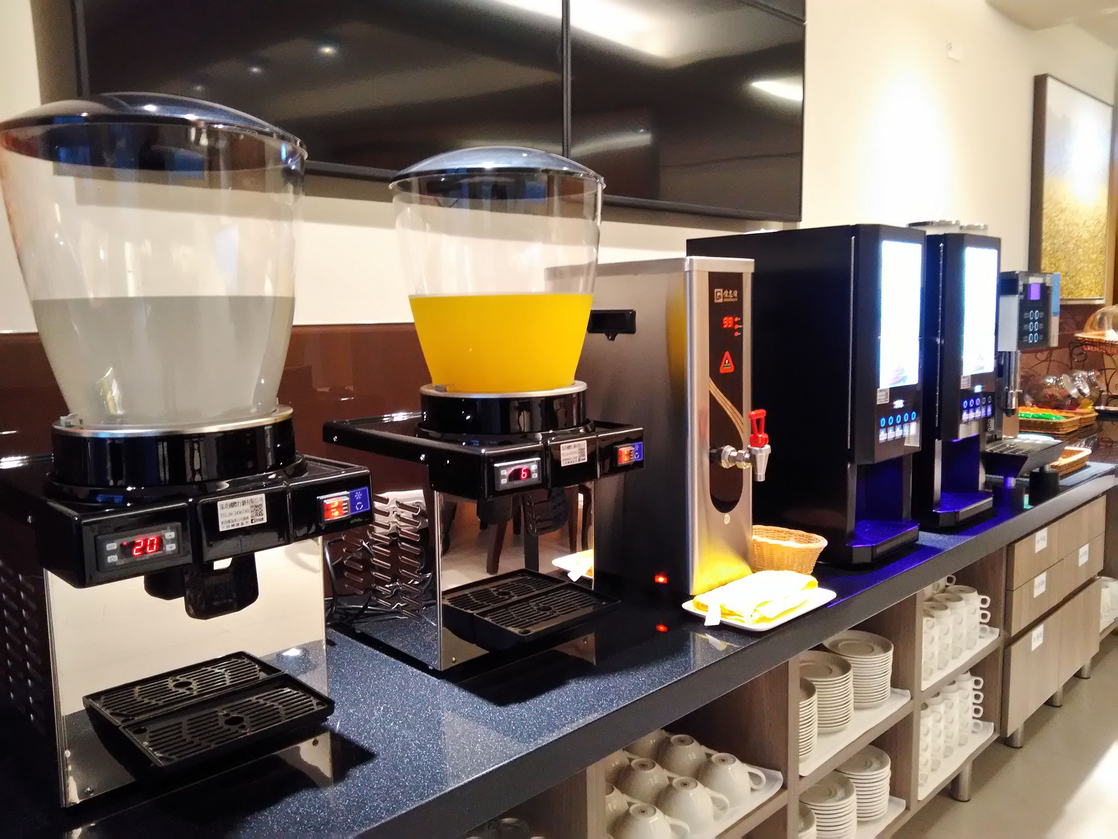 A coffee station with multiple coffee dispensers, a scale, and a basket of napkins.