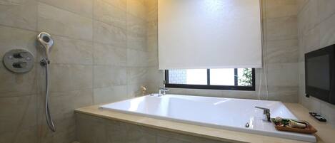 A modern bathroom with a large bathtub, a showerhead, and a window providing natural light.