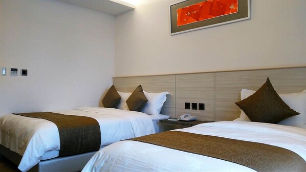 A hotel room with two beds, a bedside table with a phone, and a wall-mounted light fixture. - Dar Lon Hotel (Hsinchu)