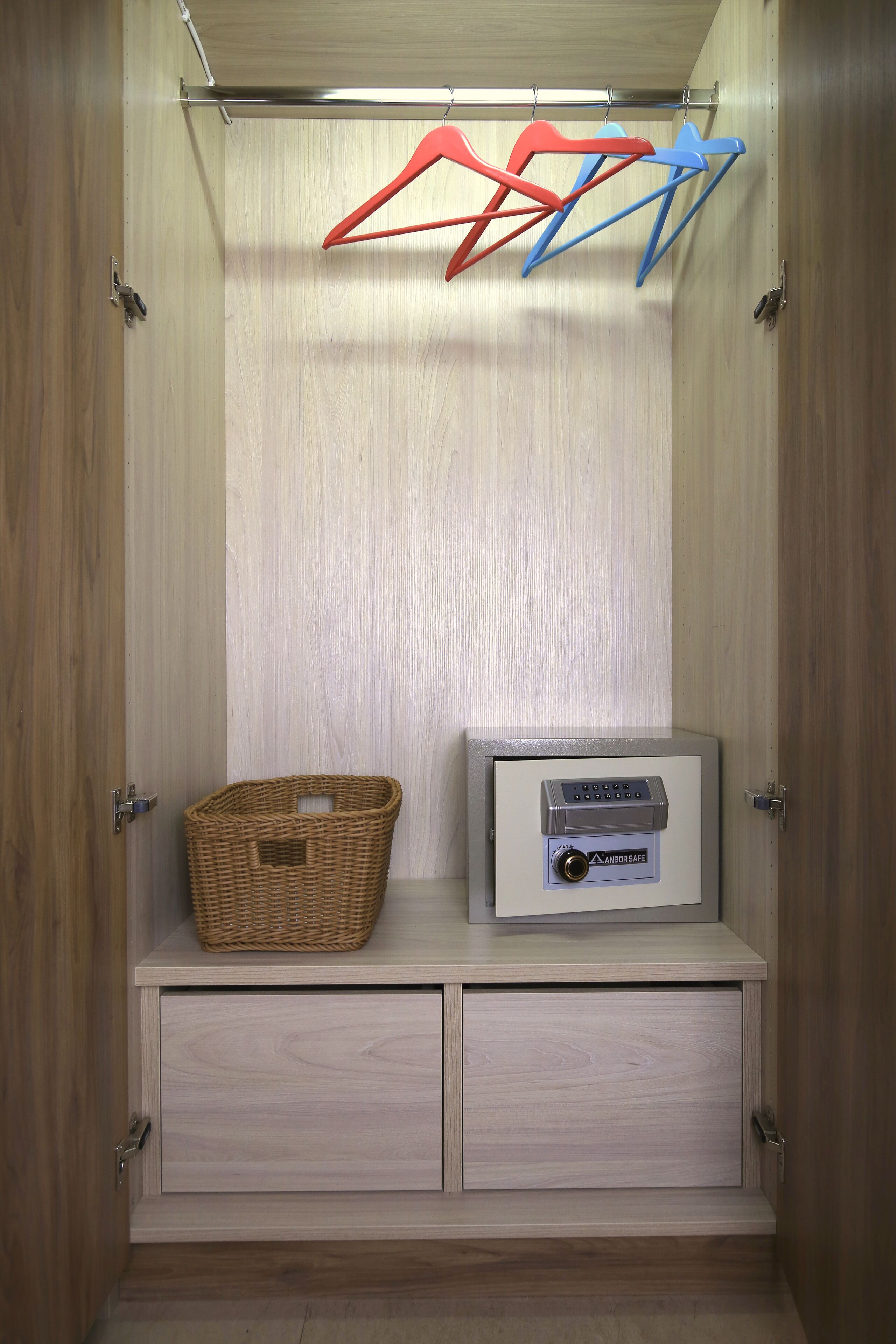 A wardrobe with a hanging organizer, a basket, and a safe.